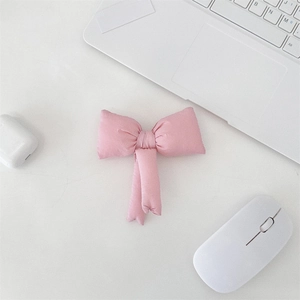 Close-up of a handmade pink fabric bow charm accessory on a minimalist white desk setup