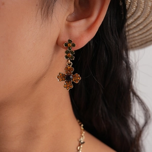 Macro shot of vintage cross earrings featuring colorful rhinestones on a model