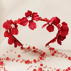 Detailed view of red fabric flowers and glossy beads on a silk-wrapped floral headband