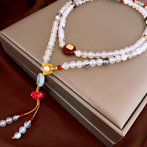 Close-up of multi-layer beaded pearl necklace with golden flower and red heart tassel