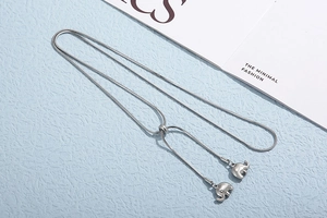Macro detail of adjustable silver snake chain with two 3D elephant charms on blue background