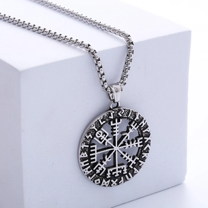 Collana con bussola vichinga d'argento e incisioni runiche su un blocco bianco minimale