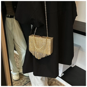 Golden evening clutch with rhinestone tassels and metal chain shown on model in mirror