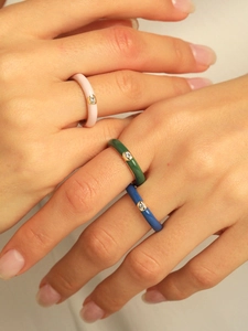 Detail view of colorful enamel rings stacked with cubic zirconia inlays on hand