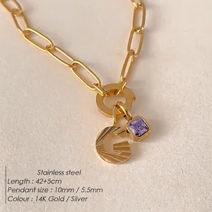 Collana a catena in acciaio dorato con ciondolo lettera G e pietra viola.