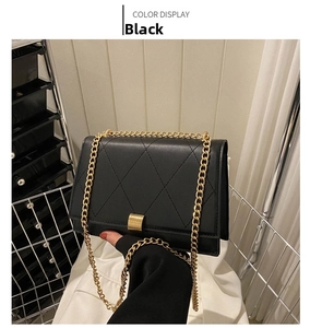 Close-up of black quilted leather shoulder bag featuring a gold square metal lock and chain