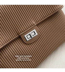 Close-up of silver metal twist lock on brown striped textured leather shoulder bag