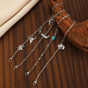Detail of silver necklaces with bull head, cactus, and boot charms on wood