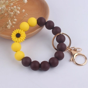 Detailed view of yellow sunflower silicone bead bracelet with golden metal key ring