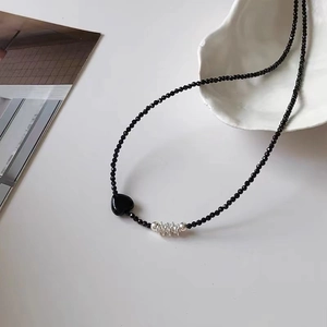 Elegant beaded heart necklace with silver spiral accents on a clean white surface