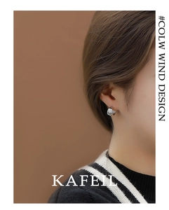 Detail of layered S925 silver C-shape earring worn by model on a brown background