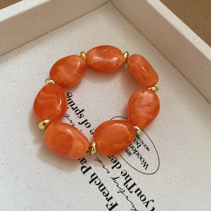 Detailed macro of orange marble acrylic oval beads with golden metal spacers