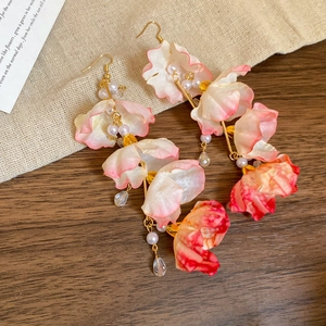 Détail de boucles d'oreilles fleurs en tissu avec perles et cristaux dorés