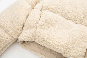 Gros plan sur la texture sherpa blanc cassé et les coutures de la veste polaire
