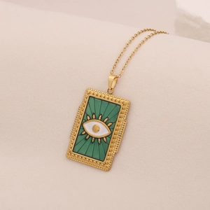 Détail d'un pendentif œil maléfique doré avec émail vert sur une fine chaîne dorée