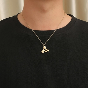 Close-up of golden bow pendant on a fine cross chain worn over a black shirt