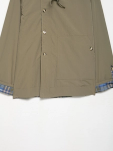 Detail view of khaki jacket showing plaid lining, button closure and cargo pocket