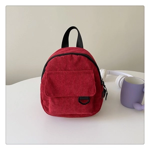 Detail of red corduroy mini backpack featuring vintage design and front buckle pocket