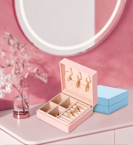 Pink and blue jewelry boxes with ring slots and earring hooks in a vanity setting