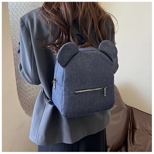 Blue denim backpack with bear ears design shown being worn in a casual lifestyle setting