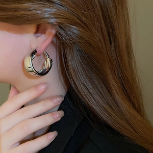 Close-up of polished silver wide hoop earring showing reflective metallic luster