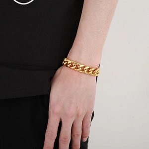Close-up of a chunky golden Cuban link bracelet worn on a wrist for a hip-hop style look