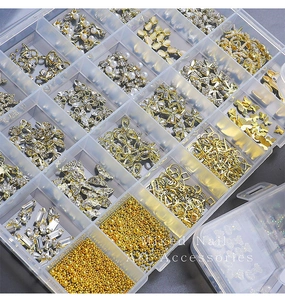 Macro view of 24-grid box containing mixed gold and silver nail art rhinestones and charms