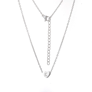 Détail d'un pendentif cœur en argent avec gravure de la lettre K sur chaîne