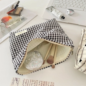 Détail de la trousse de maquillage à carreaux avec broderie florale et intérieur spacieux