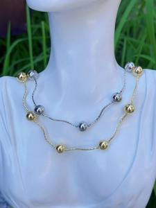 Detail view of double-layer gold and silver plated bead necklaces on a model