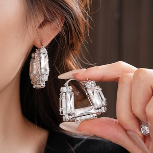 Gros plan de boucles d'oreilles argentées en U avec cristaux sur une oreille