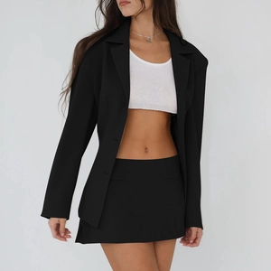 Detail of the high-waisted black mini skirt and matching cardigan set on a model