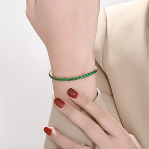 Elegant 4mm gold tennis bracelet with emerald green zircons worn on model wrist