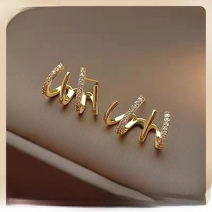 Detailed macro view of gold-plated triple claw earrings with shimmering zircon pavé