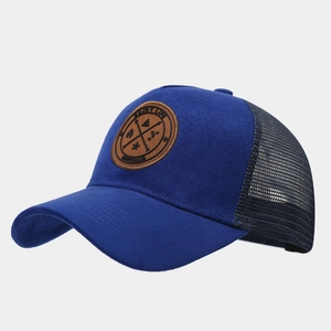 Gros plan de l'écusson en cuir marron sur la casquette en daim bleu marine