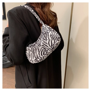 Vue latérale du sac baguette à rayures zèbre porté à l'épaule avec un blazer noir chic