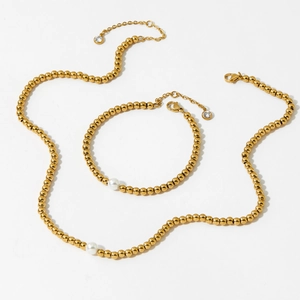 Elegant gold beaded jewelry set with white pearls and zircon pendants on white background