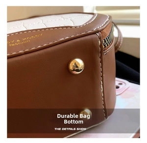 Detail showing the brown leather bag base with crocodile texture and gold protective studs