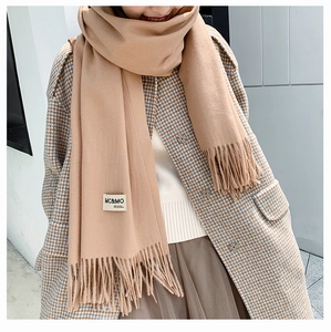 Detail of khaki cashmere-feel scarf featuring elegant tassels and material brand label
