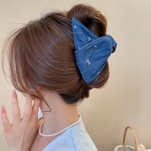 Detail of blue denim bow hair claw clip with butterfly embroidery on model's hair