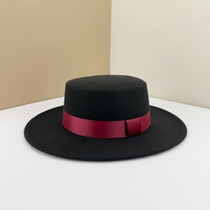 Close-up of a black wool boater hat featuring a burgundy grosgrain ribbon trim detail