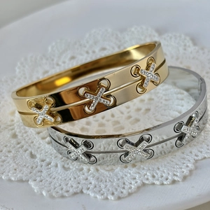 Crossed gold and silver titanium steel bracelets with pavé diamonds on lace surface