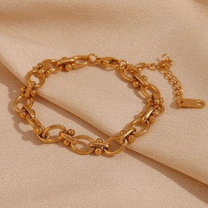 Gros plan sur un bracelet à maillons en U plaqué or 18 carats avec billes sur satin rose