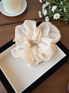 Dettaglio dell'elastico scrunchie oversize in organza beige crema effetto perlato