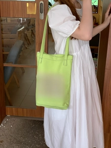 Detail of neon green canvas tote bag featuring repeated blue HAPPY HAPPY lettering