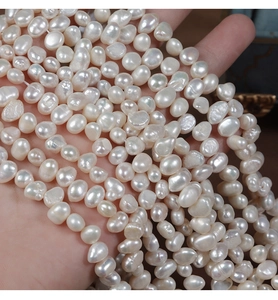 Hand holding natural baroque freshwater pearls showing 6-7mm size and glossy luster