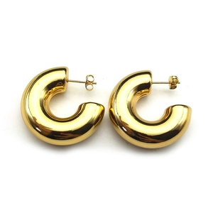 Detailed view of chunky gold-plated C-shaped earrings with high-polish mirror finish