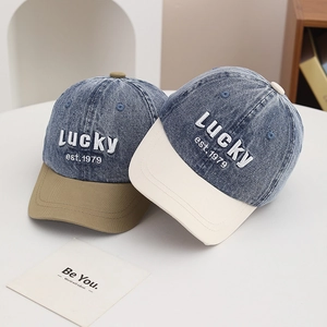 Detail of kids washed denim baseball caps with Lucky est. 1979 3D embroidery on surface