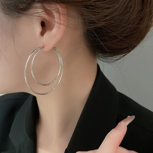 Close-up of double-layer silver hoop earrings worn by a model in a professional setting