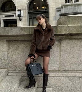 Manteau en fausse fourrure marron foncé avec bottes en cuir noires et sac à main de ville